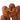 A rough, textured gold nugget or gold-rich rock specimen held between human fingers against a plain white background.