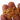 A close-up of a rough, textured gold piece held between fingers against a plain white background.